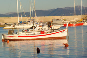 Rød og hvitstripet trbåt fortøyde ved bøye i liten havn