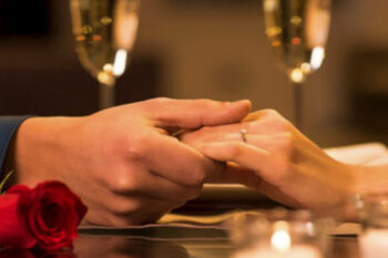 To hender holder hverandre mellom champagne-glass og roser