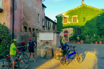 Hus dekket av blomster med to syklister på Sentiero Pasolino